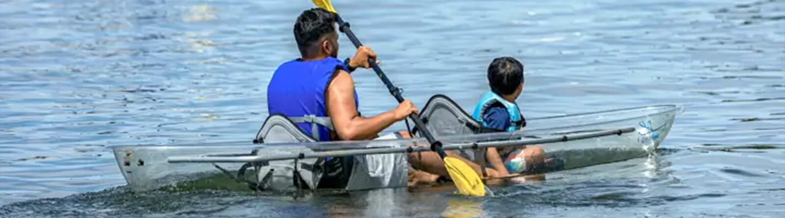 A father and son explore the Gulf waters in a clear kayak rental